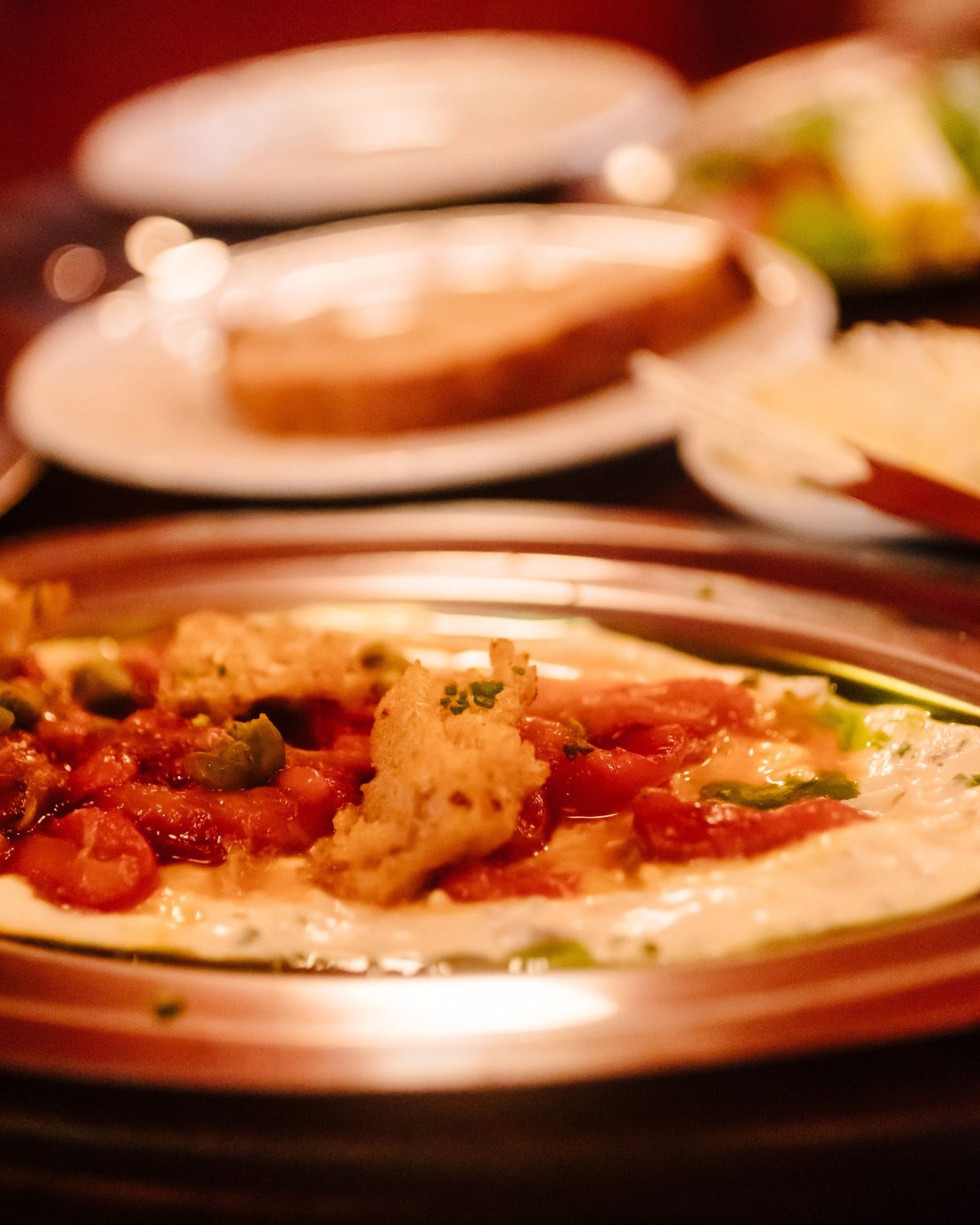 Un plato para compartir sobre una crema, con pan y otros platos de fondo.